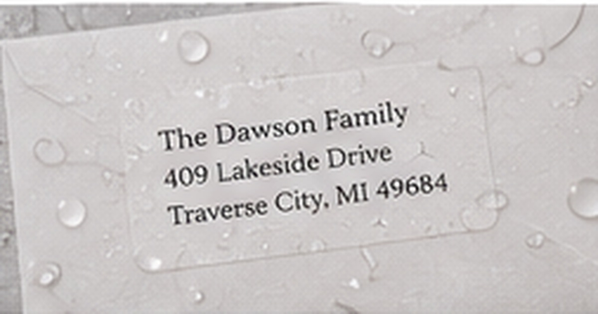 Clear address label covered with water droplets on a pale gray textured surface